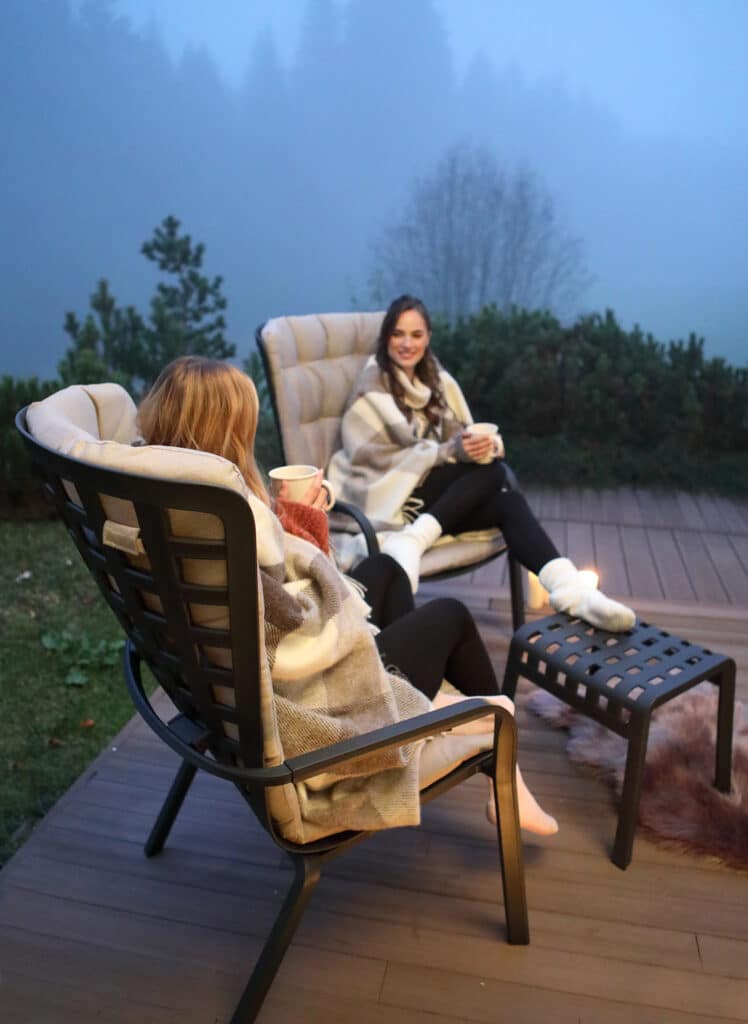 Two women sitting on outdoor chairs from Hauser's Patio