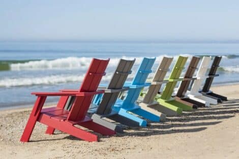 Row of colorful adirondack chairs on beach by hausers patio luxury outdoor living by hausers patio