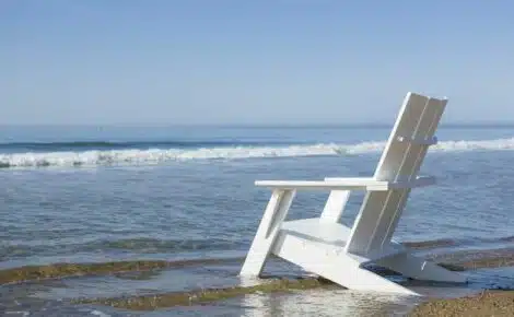 White adirondack chair on beach by hausers patio luxury outdoor living by hausers patio